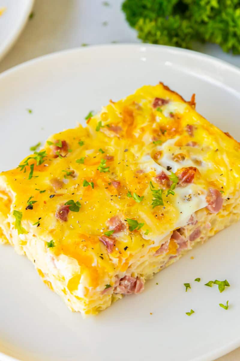 a slice of ham and cheese breakfast casserole on a white plate.