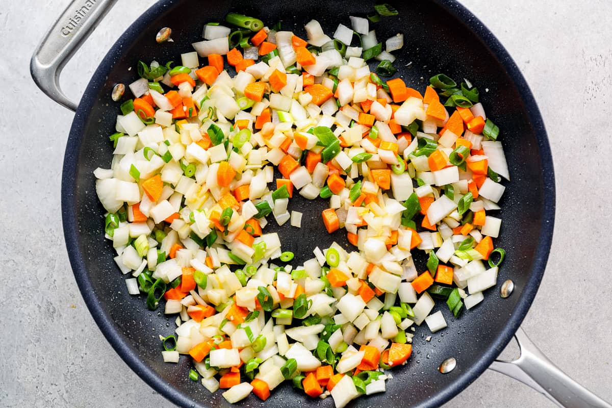 Diced veggies cooking in a skillet.