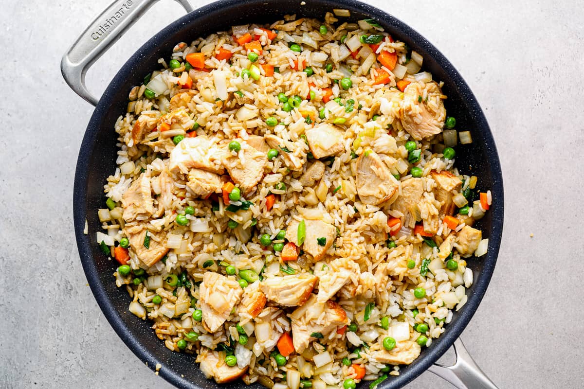 Fried rice with chicken cooking in a skillet.