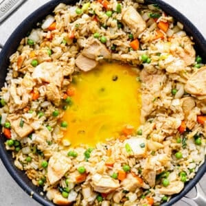 making chicken fried rice: egg yolk in the center of rice inside of a skillet