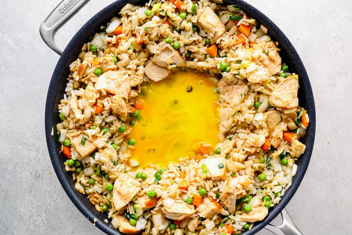 Eggs cooking at the center of a skillet of fried rice.