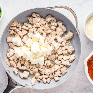 chicken thigh pieces with cream cheese in a skillet.