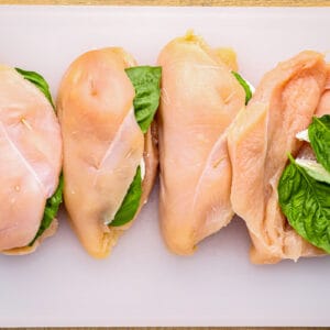 3 stuffed chicken breasts and 1 butterflied chicken breast being stuffed with mozzarella and basil.