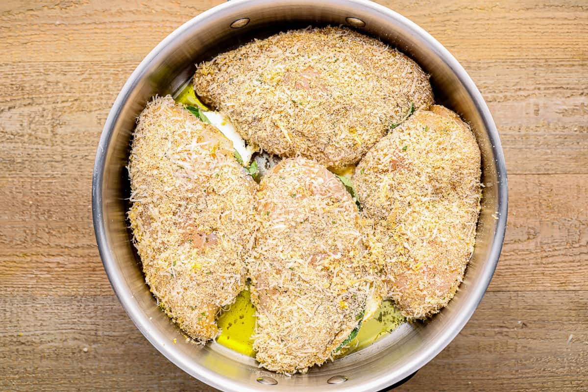 4 breadcrumb coated chicken breasts in a pan.
