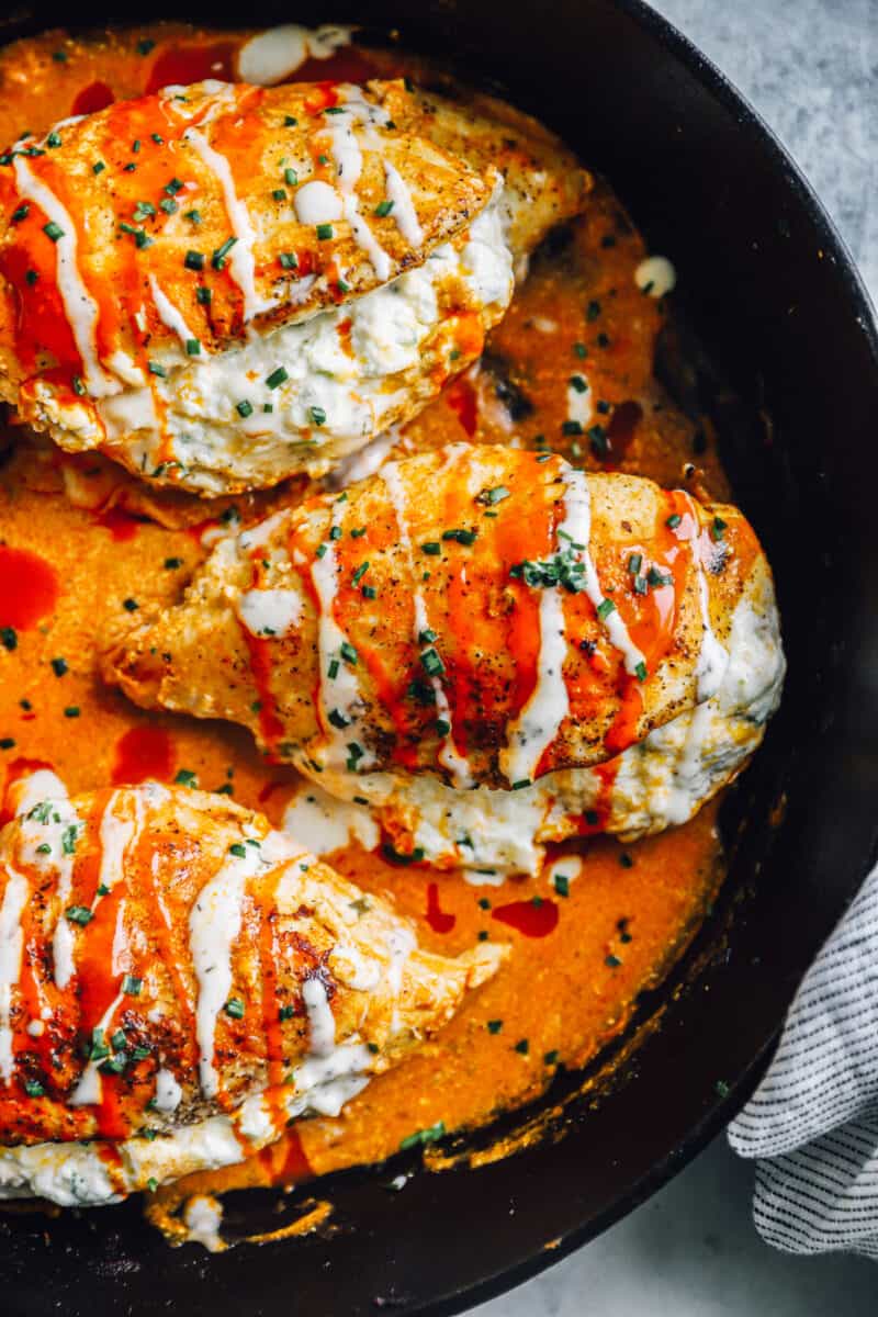 close up of stuffed buffalo chicken breasts in a skillet.
