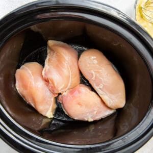 raw chicken breast in the bottom of a slow cooker