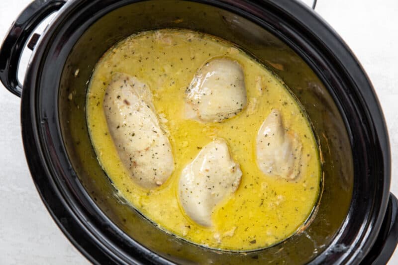 chicken breast sitting in ranch and cream of chicken in a crockpot