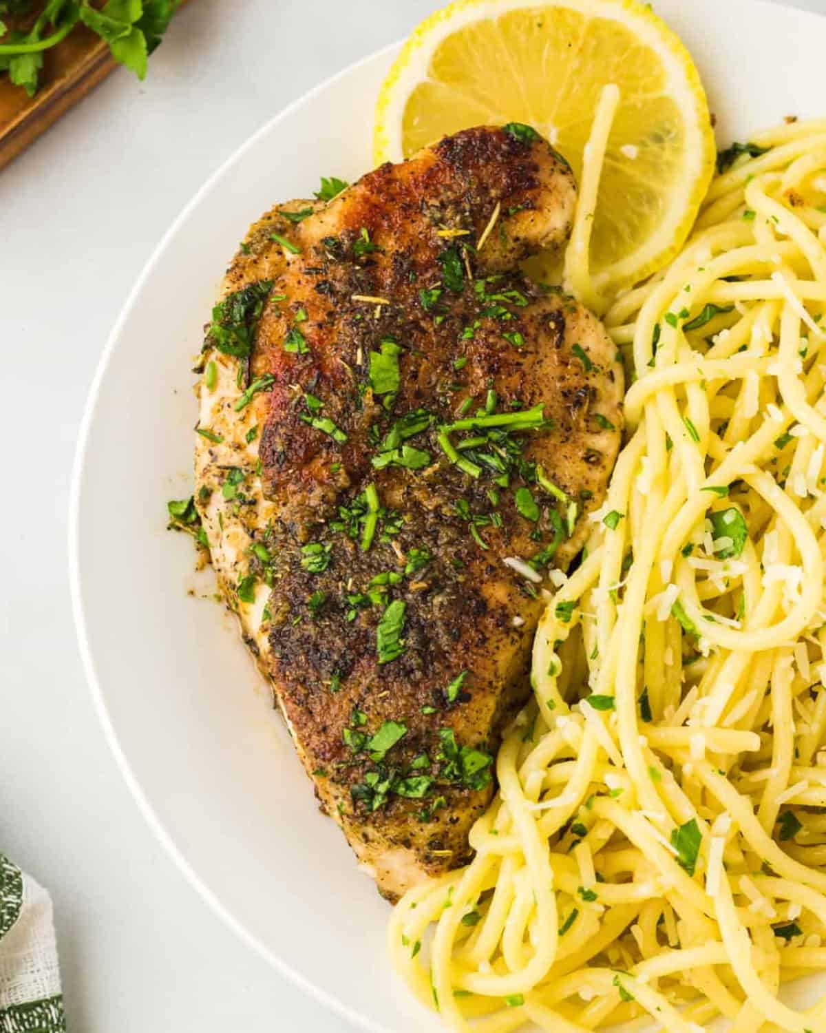 overhead view of a lemon pepper chicken cutlet on a plate with pasta.