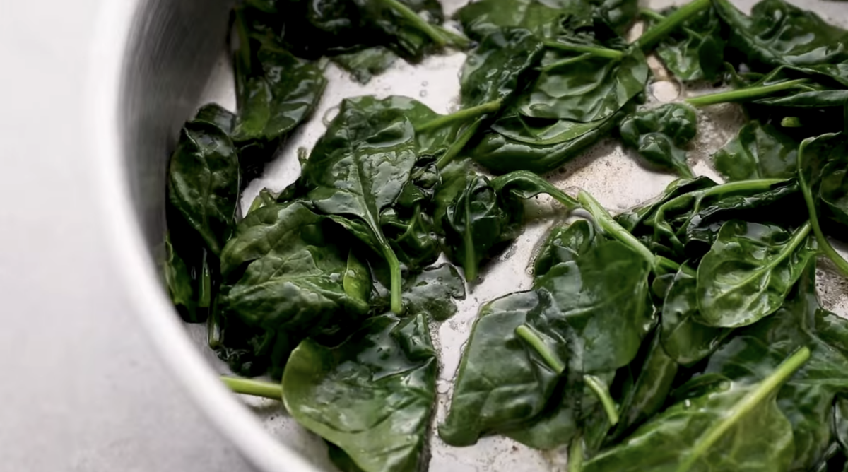 Spinach is being cooked in a skillet. 