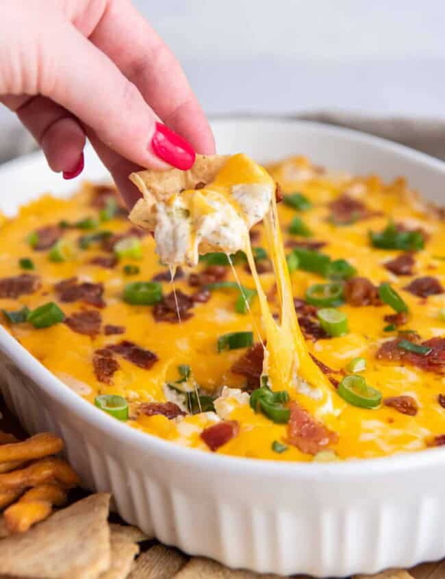 hand dipping a tortilla chip into crack chicken dip