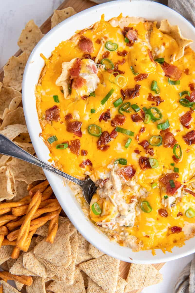 crack chicken dip in on a platter with various chips and crackers