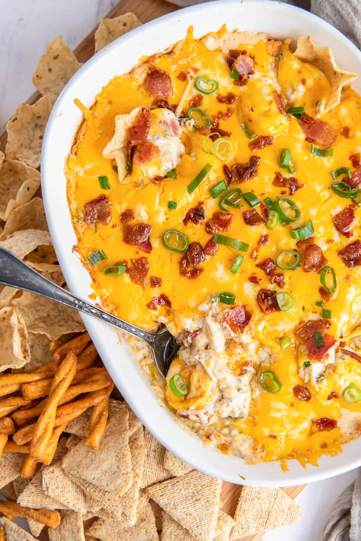 Baked crack dip topped with bacon, green onions, and cheese.