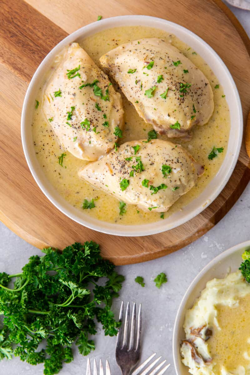 plate of crockpot ranch chicken breast, sitting on a wooden cutting board