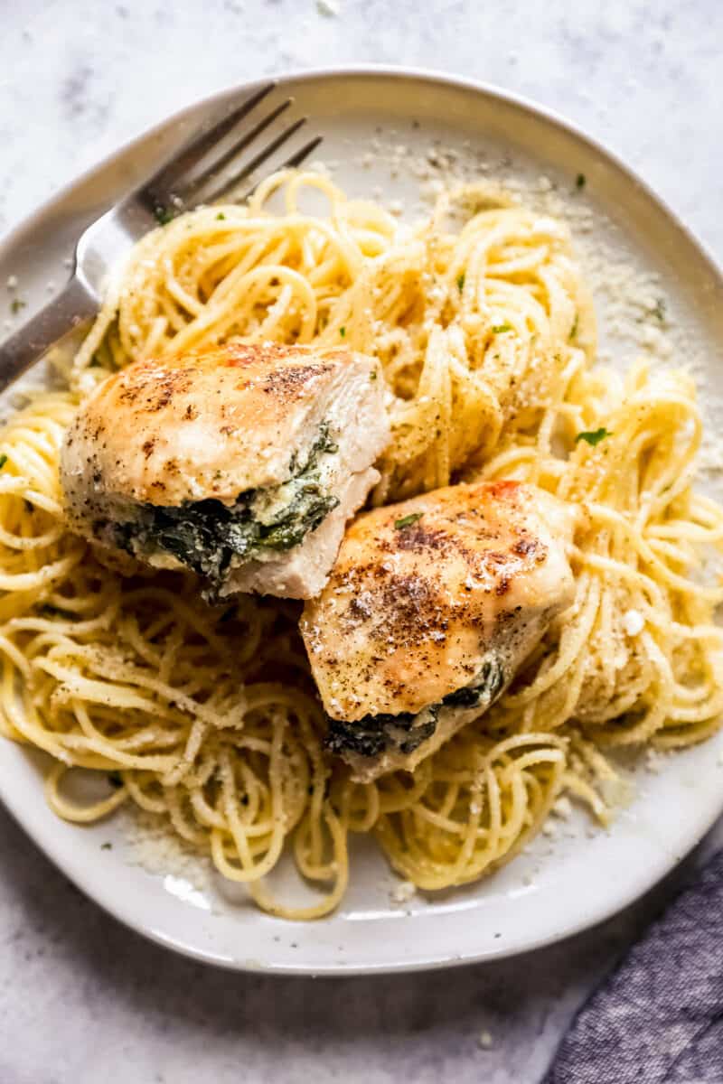 a plate of spaghetti with stuffed chicken on top