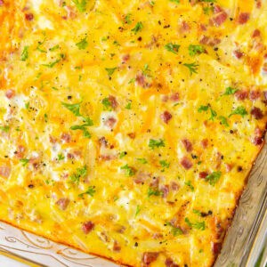 cropped overhead view of a ham and cheese breakfast casserole in a glass baking pan.
