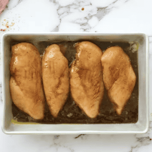 Baked chicken breasts in a pan with lemons and spices.