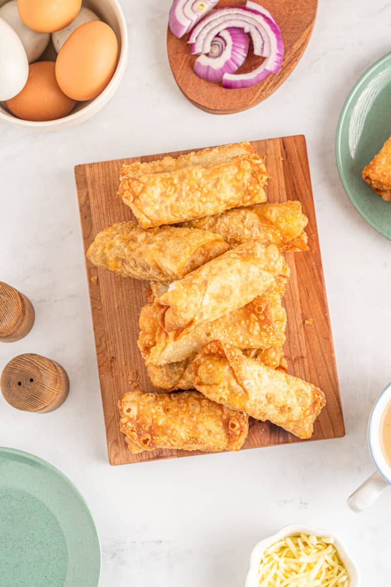 breakfast egg rolls piled up on a cutting board at the center