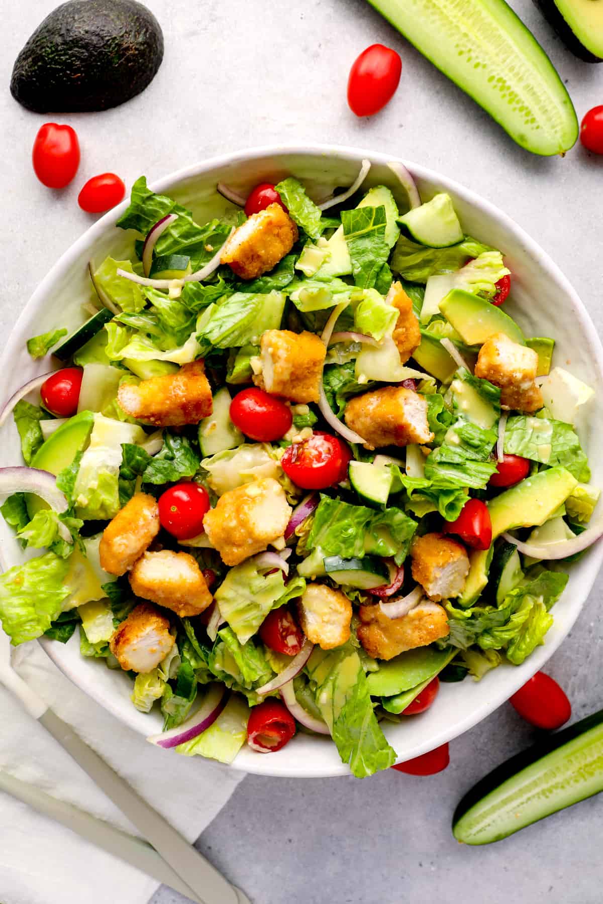 overhead view of a crispy chicken salad with tomatoes and croutons