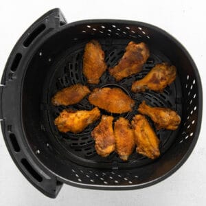 cooked chicken wings in an air fryer basket