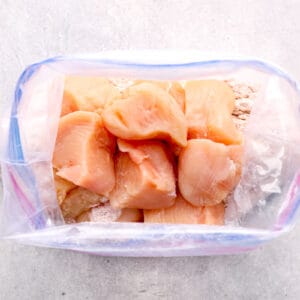 raw chicken pieces inside of a bag with seasoning mixture