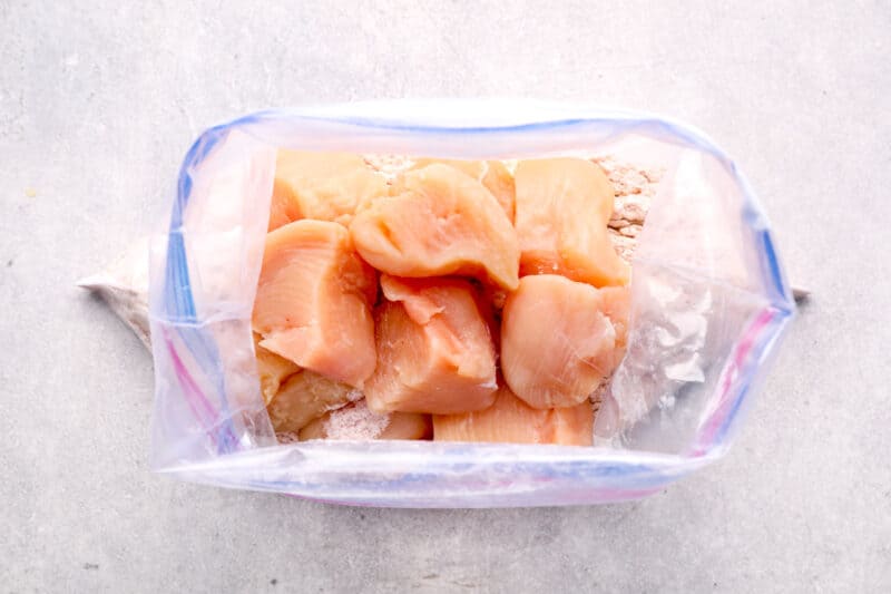 raw chicken pieces inside of a bag with seasoning mixture