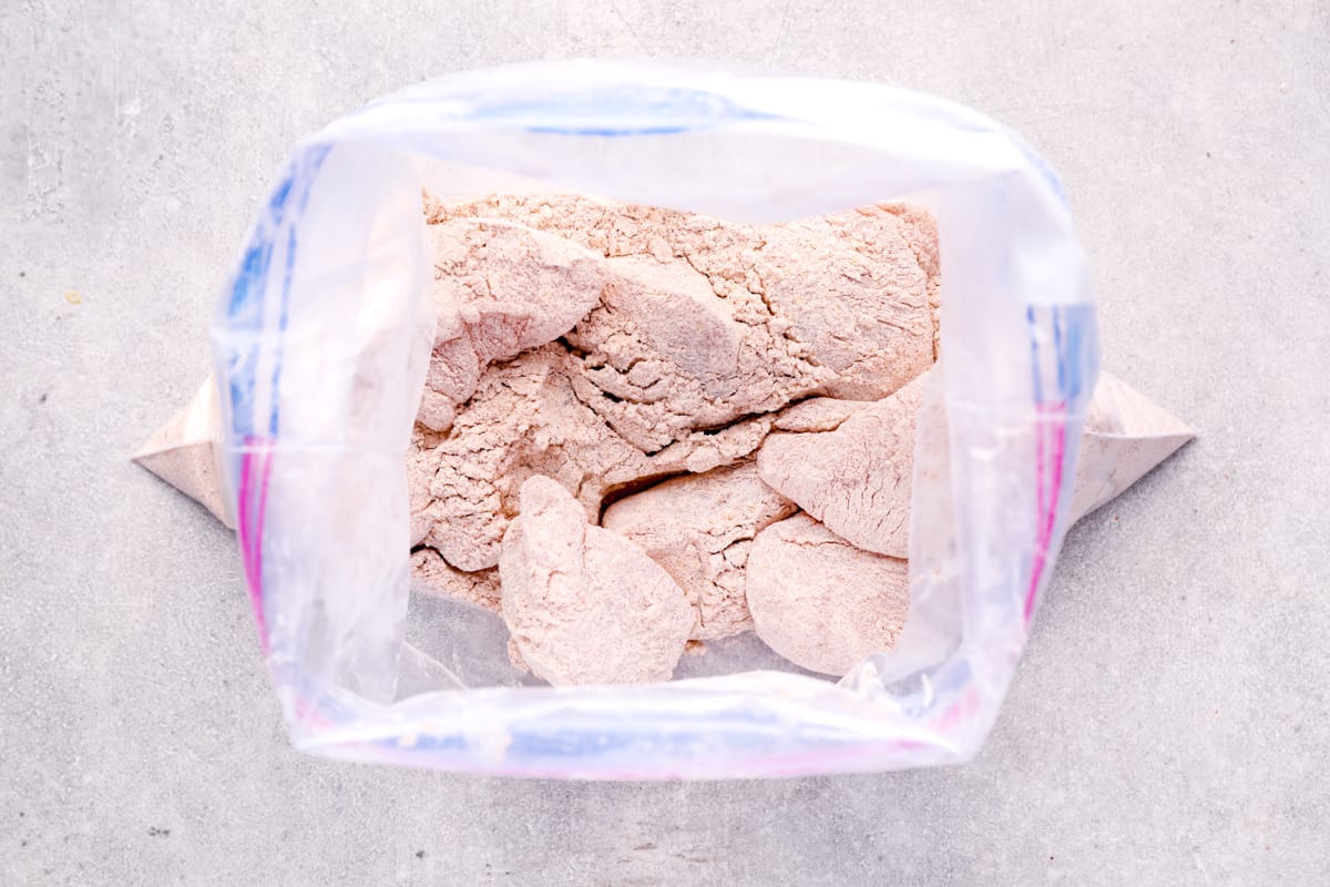 view into a resealable plastic bag filled with chicken wings covered in a flour seasoning mix