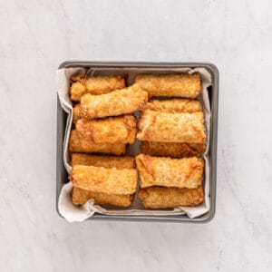 cooked egg rolls piled up in a pan