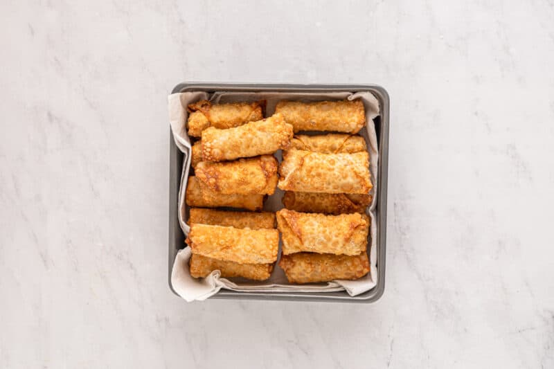cooked egg rolls piled up in a pan