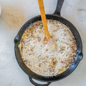 mixing cream into a sauce in a skillet