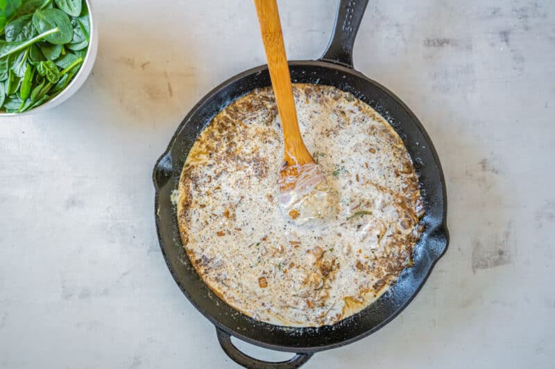 mixing cream into a sauce in a skillet