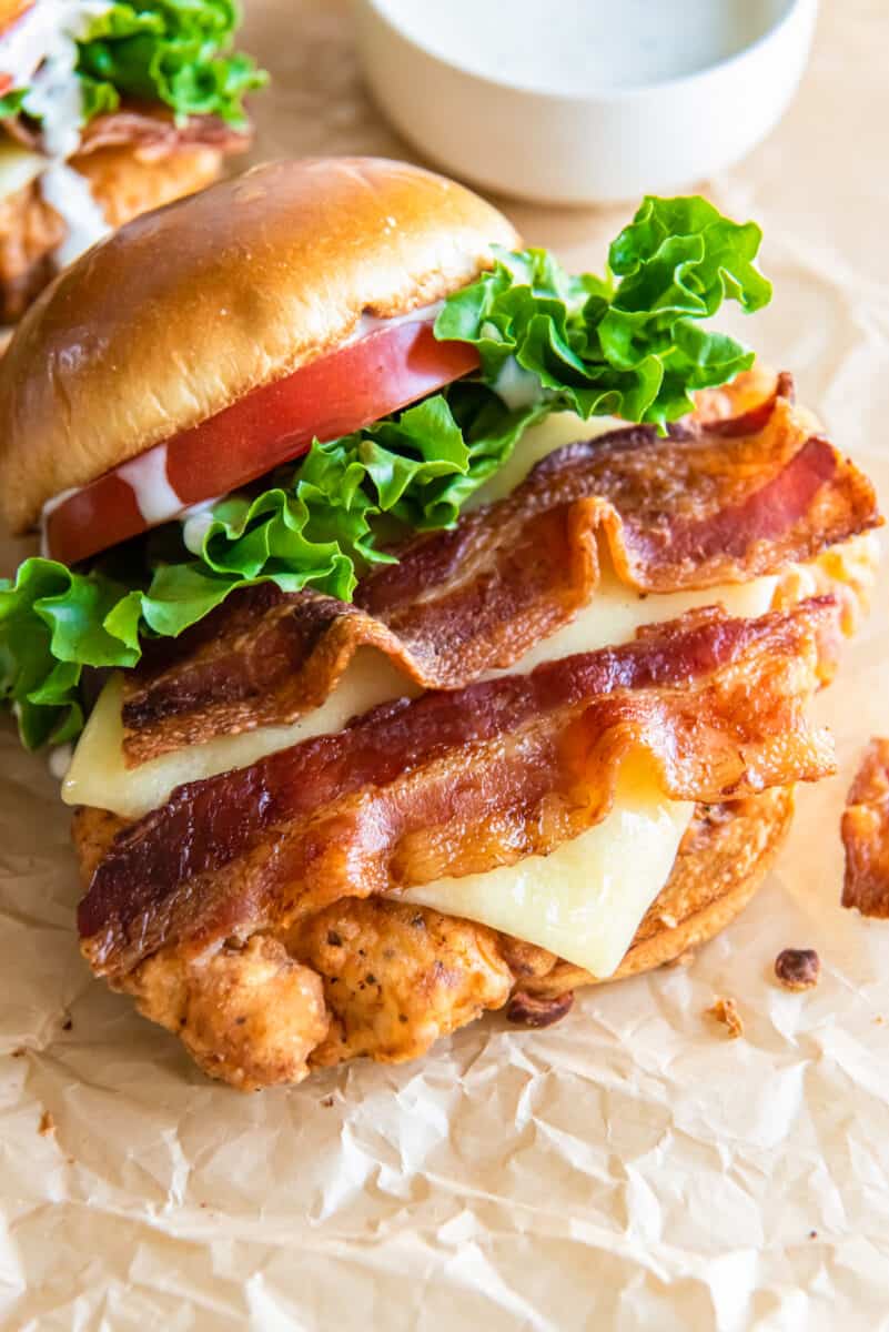 chicken club sandwich topped with slices of bacon and asiago cheese