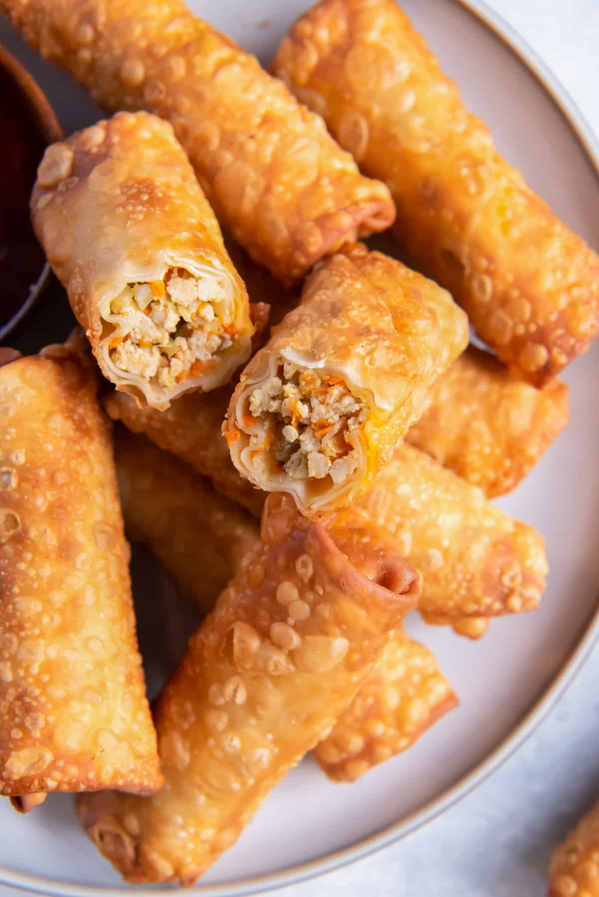 close up on a plate of egg rolls, one is cut in half to show the filling