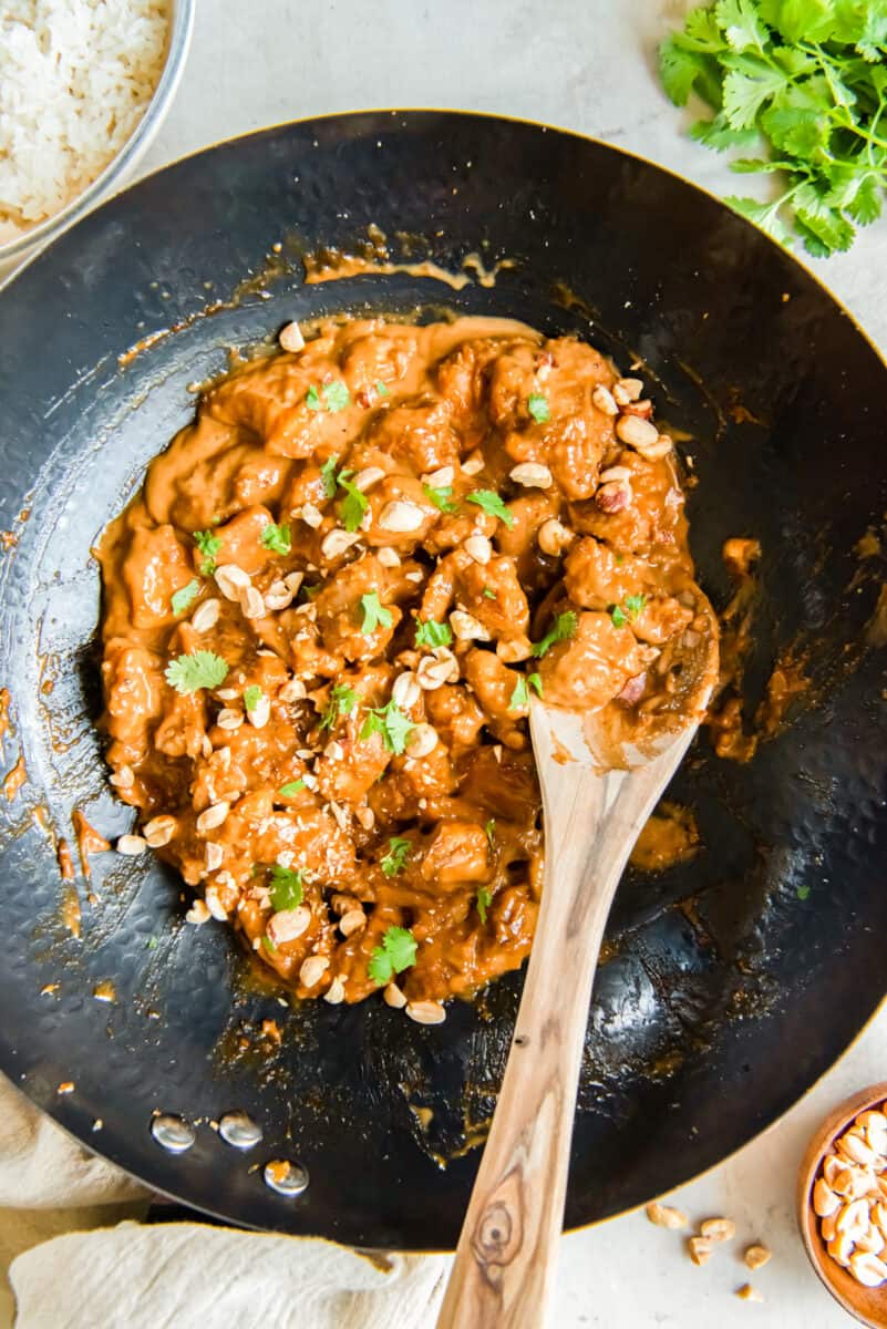 cooking chicken with peanut sauce in a wok