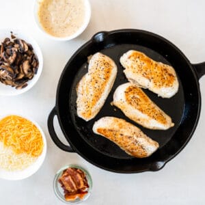 four sautéed chicken breasts in a cast iron skillet