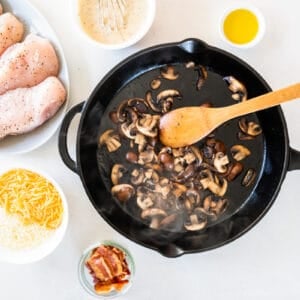sautéing mushrooms in a skillet, surrounded by bowls of ingredients