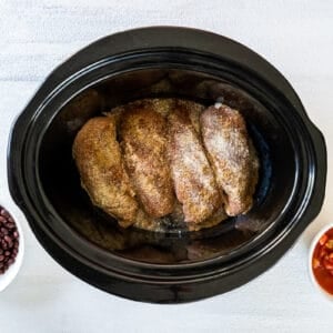 seasoned chicken breasts lined up in a slow cooker