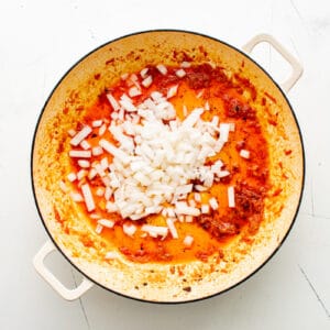 a pan with onions and tomatoes in it.