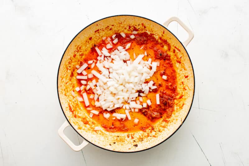 a pan with onions and tomatoes in it.