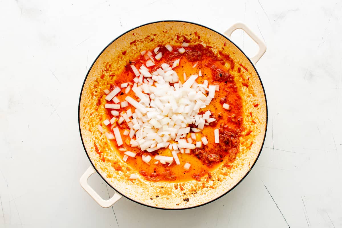 a pan with onions and tomatoes in it.