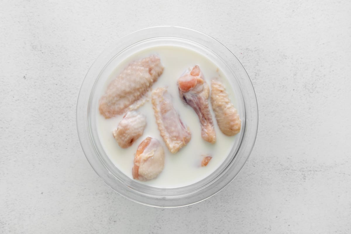 Raw chicken wings soaking in buttermilk.