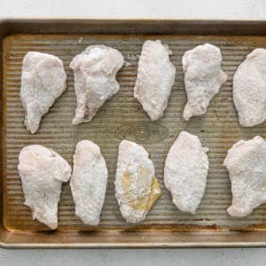flour-coated chicken wings on a baking tray