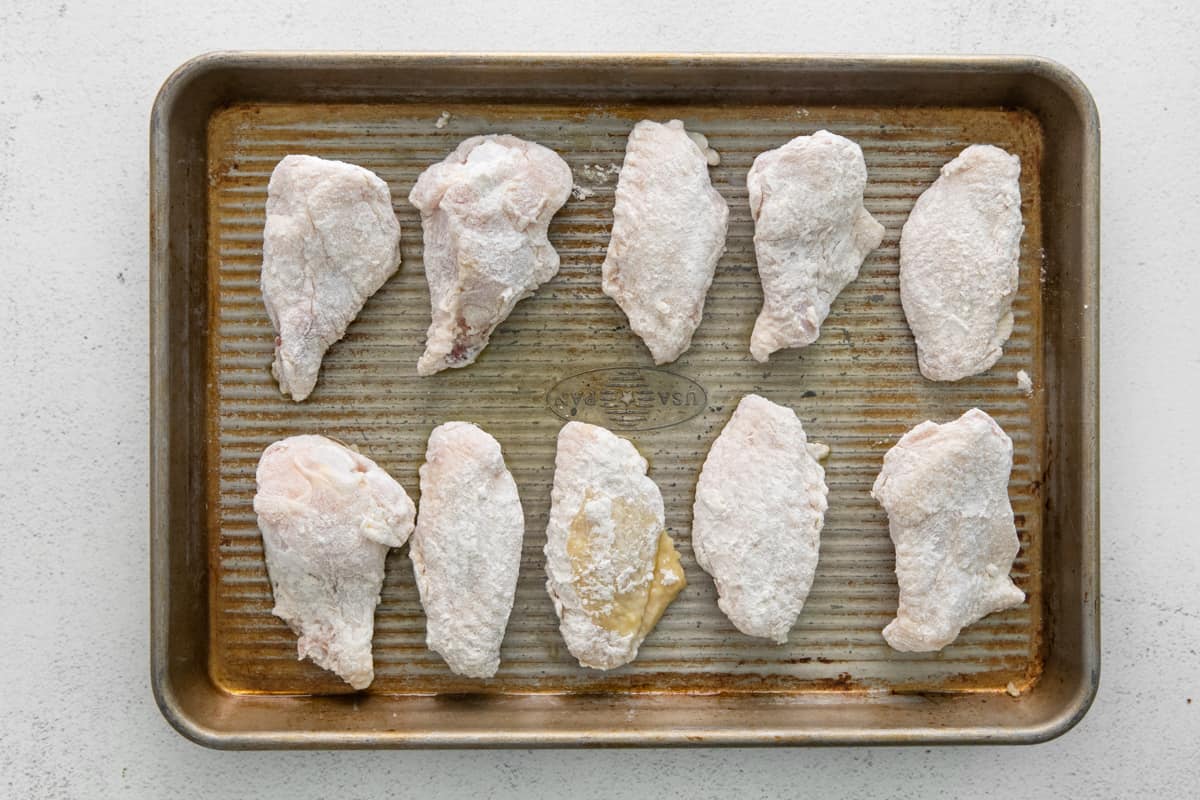 Flour-coated chicken wings on a baking tray.