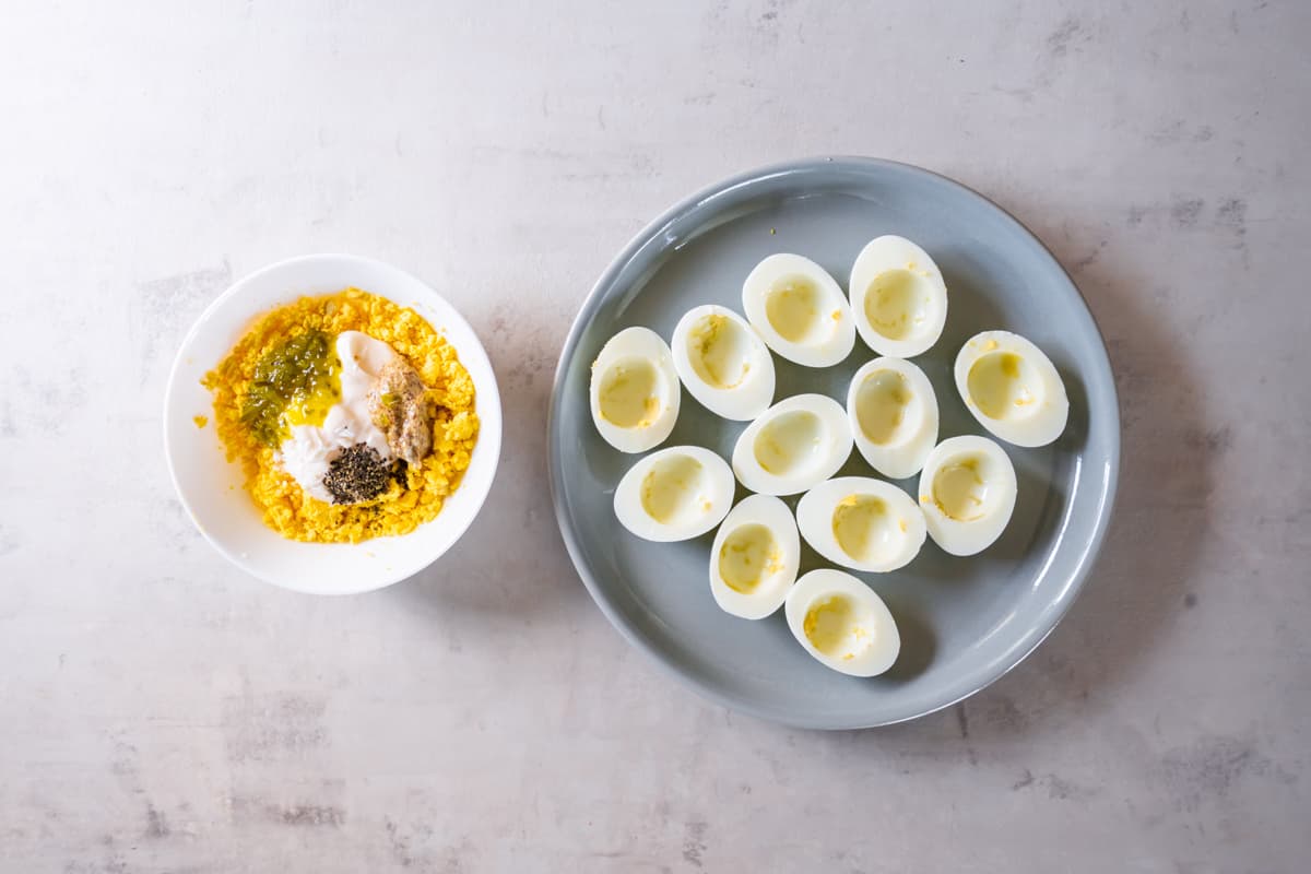 hardboiled eggs cut in half, next to a bowl of egg yolk with seasonings