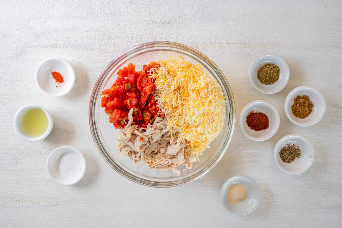 Shredded chicken, cheese, and tomato filling in a mixing bowl.