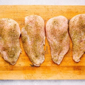 seasoned chicken breasts lined up on a cutting board