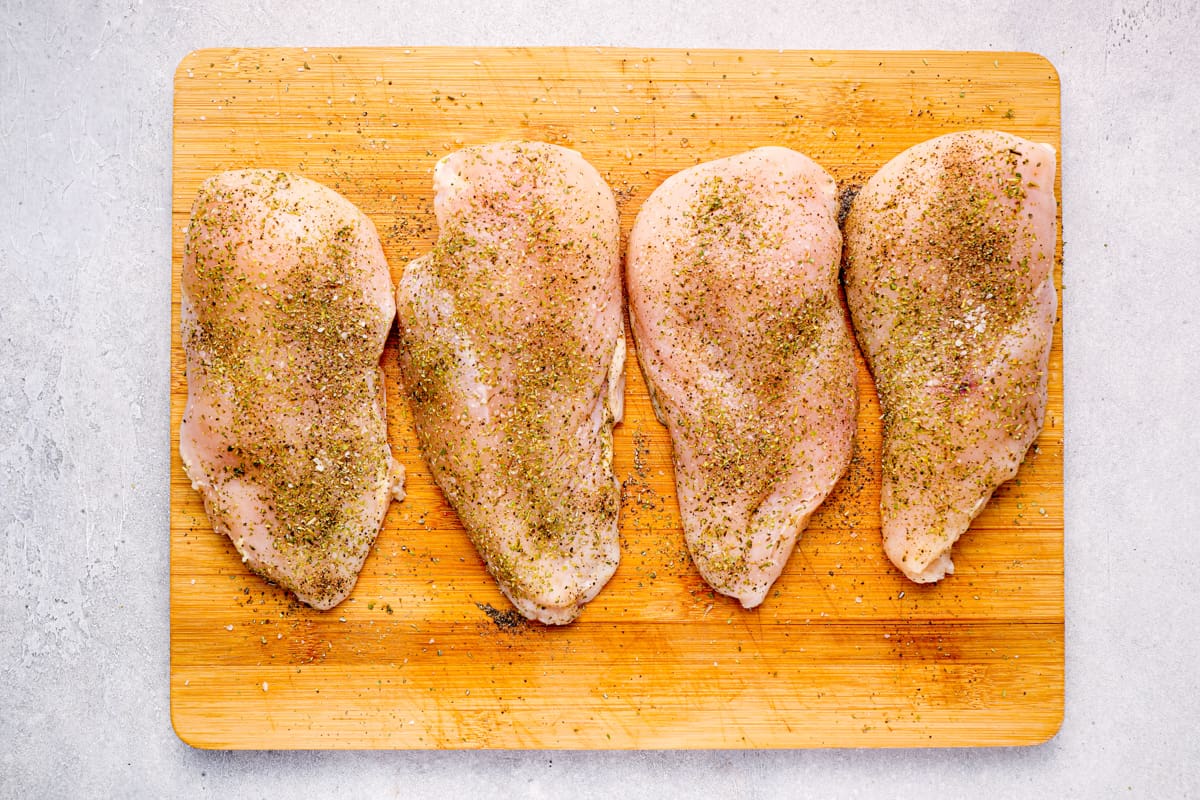 seasoned chicken breasts lined up on a cutting board