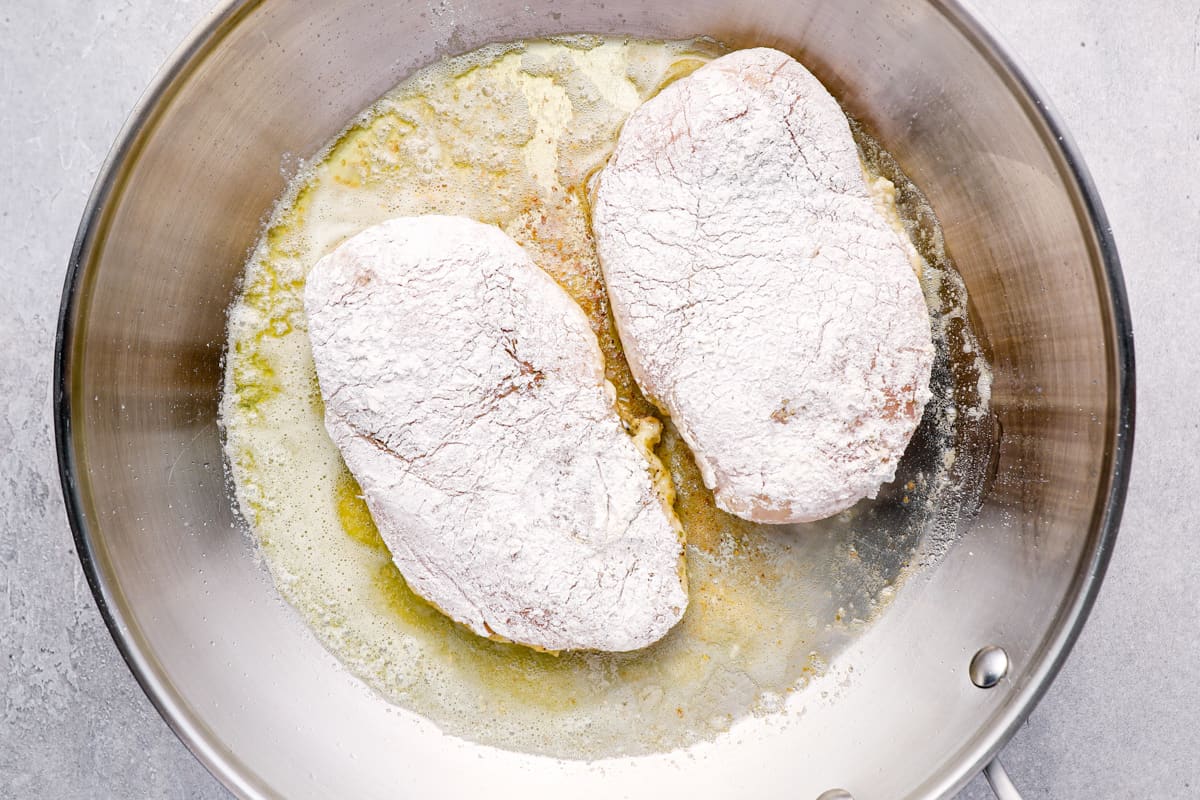 breaded chicken breasts frying in a pan