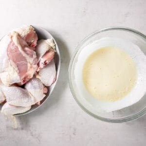 plate of raw chicken next to a bowl of buttermilk