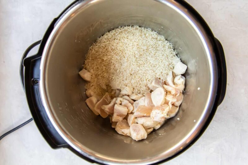 uncooked cubed chicken and rice in a pressure cooker