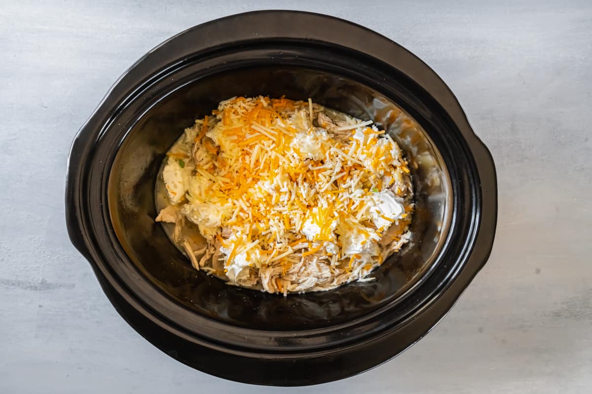 cooked chicken in the slow cooker, covered shredded cheese